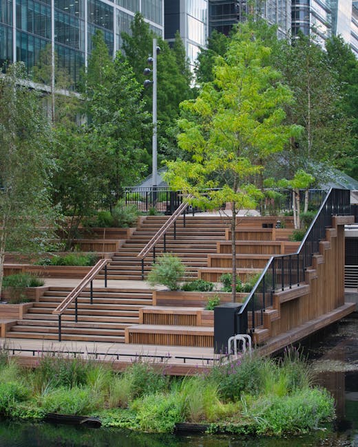 A multi-tiered wooden terrace with wide, evenly spaced steps and black metal handrails, set amidst lush greenery in an urban outdoor space. The terrace features several small garden beds filled with a